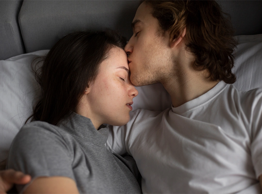 man-kissing-woman-s-forehead-bed